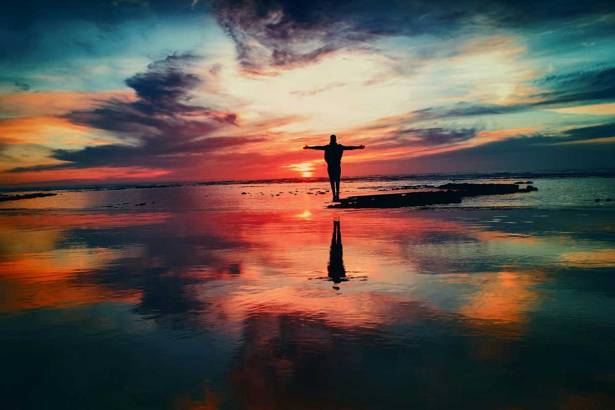 Person standing with arms wide open at sunset, symbolizing calmness before starting individual therapy