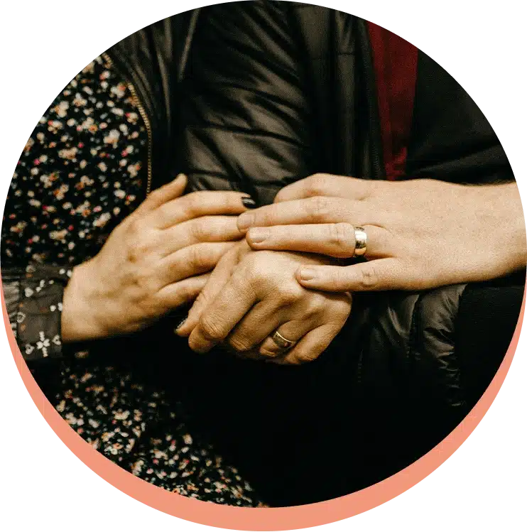 Close-up of a couple's **intertwined hands** showing wedding rings.